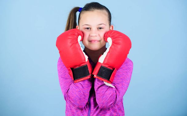 Contrary to stereotype. Boxer child in boxing gloves. Female boxer. Sport upbringing. Boxing provide strict discipline. Girl cute boxer on blue background. With great power comes great responsibility - Фото, изображение