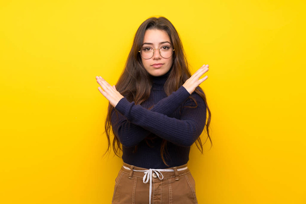 Teenager girl over isolated yellow wall making NO gesture - Foto, Bild