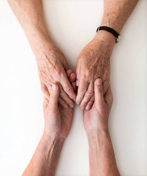 Krankenschwester tröstet ihre ältere Patientin, indem sie ihre Hände hält - Foto, Bild