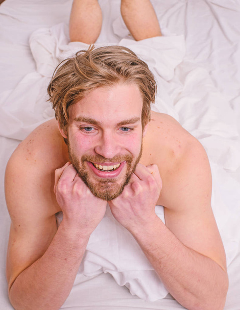 Pleasant relax concept. Let your body feel comfortable. Man unshaven handsome happy smiling torso relaxing bed. Man feel full of energy after pleasant night dream. Guy sexy macho lay white bedclothes - Фото, изображение
