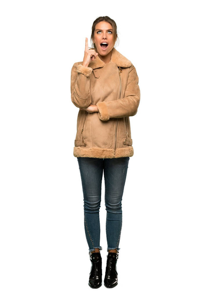 A full-length shot of a Blonde woman with a coat pointing with the index finger a great idea over isolated white background - Foto, Bild
