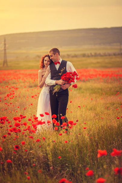 The bride and groom in a poppy field - Zdjęcie, obraz