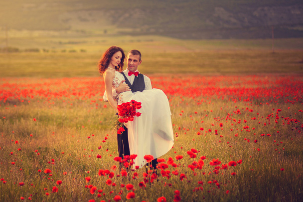 The bride and groom in a poppy field - Zdjęcie, obraz