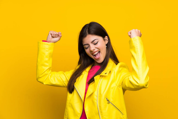 Menina adolescente sobre a parede amarela celebrando uma vitória
 - Foto, Imagem