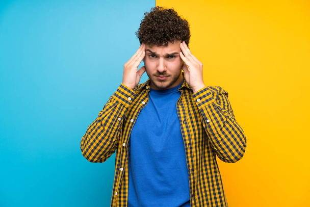 Homme aux cheveux bouclés sur un mur coloré malheureux et frustré par quelque chose. Expression faciale négative
 - Photo, image