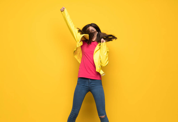 Teenager girl jumping over isolated yellow wall - Photo, Image