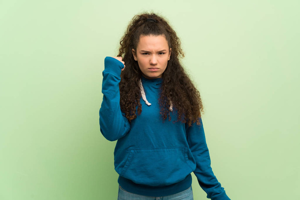 Ragazza adolescente sopra il muro verde con gesto arrabbiato
 - Foto, immagini