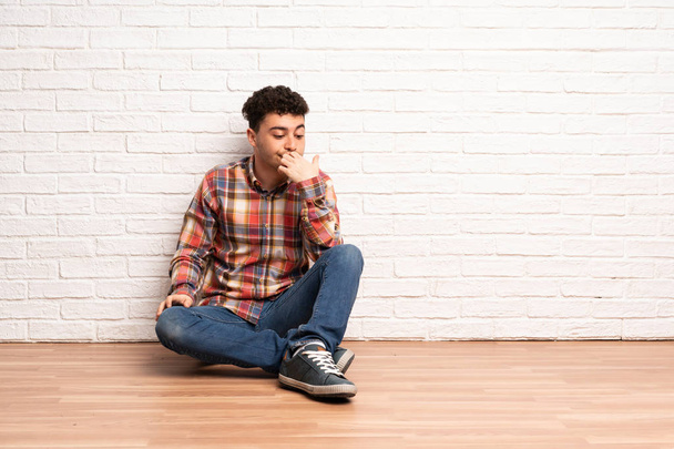 Young man sitting on the floor having doubts - Valokuva, kuva