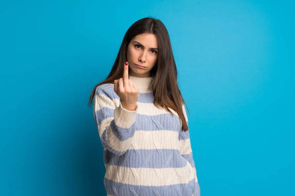 Young woman over blue wall making horn gesture - Foto, Imagem