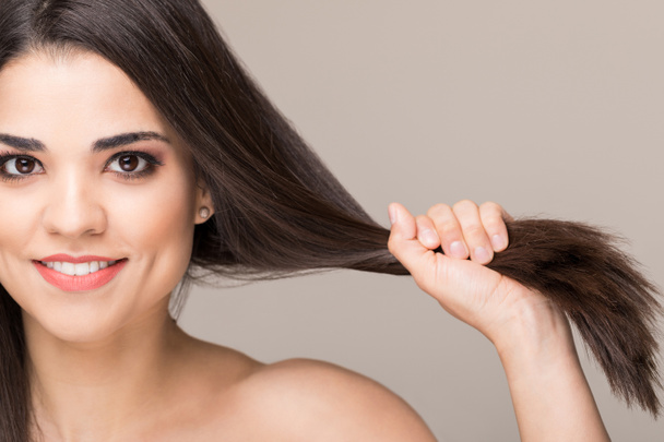 Smiling brunette showing her healthy strong hair over isolated background - Photo, Image