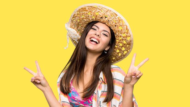 Teenager girl on summer vacation showing victory sign with both hands over isolated yellow background - Photo, Image