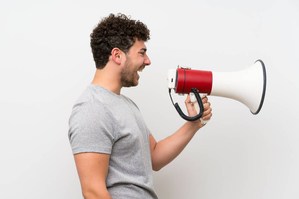 Man with curly hair over isolated wall shouting through a megaphone - Φωτογραφία, εικόνα