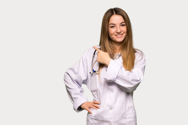 Young doctor woman pointing to the side to present a product on isolated grey background - Photo, Image
