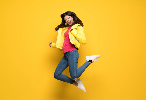 Teenager girl jumping over isolated yellow wall - Photo, Image