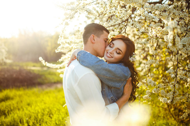 Beautiful loving couple in the blooming gardens. Wedding concept. Great sunset light. Lovely newlyweds. - 写真・画像