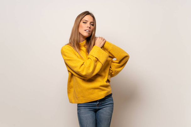 Женщина с желтым свитером над изолированной стеной страдает от боли в плече за то, что сделала усилие
 - Фото, изображение