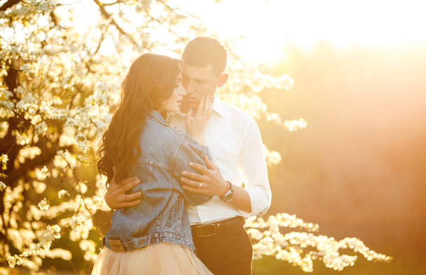 Beautiful loving couple in the blooming gardens. Wedding concept. Great sunset light. Lovely newlyweds. - Fotó, kép