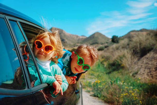 sevimli erkek ve kız dağlarda araba ile seyahat keyfini çıkarın - Fotoğraf, Görsel