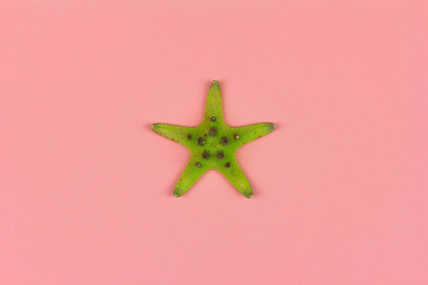 green starfish on pink background close-up, top view flat lay - Zdjęcie, obraz