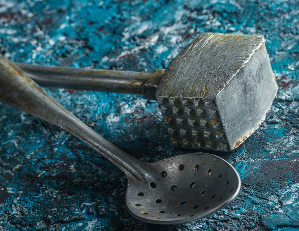 Martillo de cocina de metal viejo, cuchara de cerca sobre un fondo de hormigón azul
 - Foto, Imagen