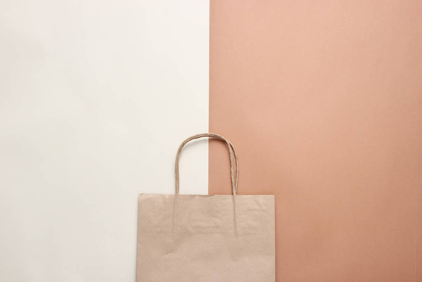Χάρτινη σακούλα για ψώνια σε μπεζ καφέ φόντο. Φθινοπωρινή αγορά, πώληση. Κορυφαία προβολή, μινιμαλισμός - Φωτογραφία, εικόνα