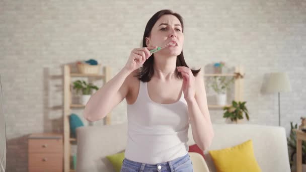 Young woman notices blood on the brush and mouth pain while brushing her teeth.The concept of bleeding gums - Metraje, vídeo