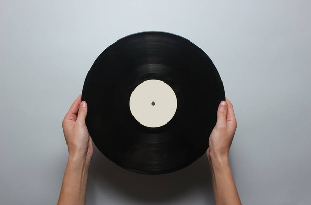 Mains féminines tenant un disque vinyle rétro sur fond gris. Vue d'en haut, minimalisme
. - Photo, image