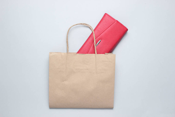 Τσάντα για ψώνια με χαρτί, κόκκινο δερμάτινο πορτοφόλι σε γκρίζο φόντο. Κορυφαία προβολή - Φωτογραφία, εικόνα