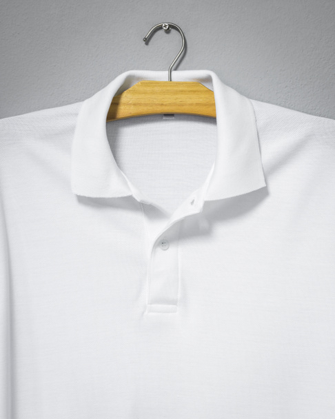 Primer plano de camisa blanca colgando en la pared de cemento. Camiseta en blanco para imprimir
. - Foto, imagen