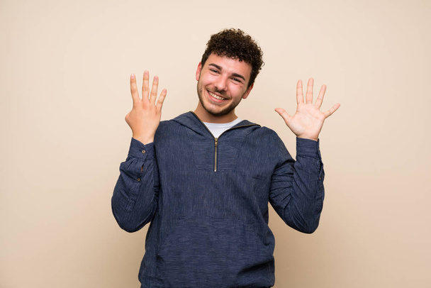Άνθρωπος με σγουρά μαλλιά πάνω από απομονωμένο τοίχο μετρώντας εννιά με δάχτυλα - Φωτογραφία, εικόνα