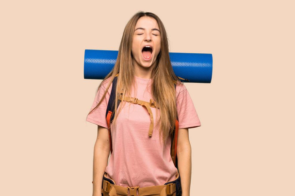 Young backpacker woman shouting to the front with mouth wide open on isolated yellow background - Foto, imagen