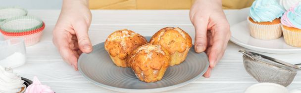 panoramic shot of woman holding plate with muffins on table - Foto, immagini