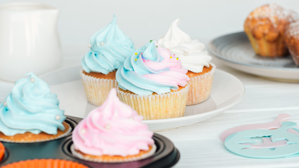 delicious cupcakes decorated with colorful frosting on plate isolated on grey - Valokuva, kuva