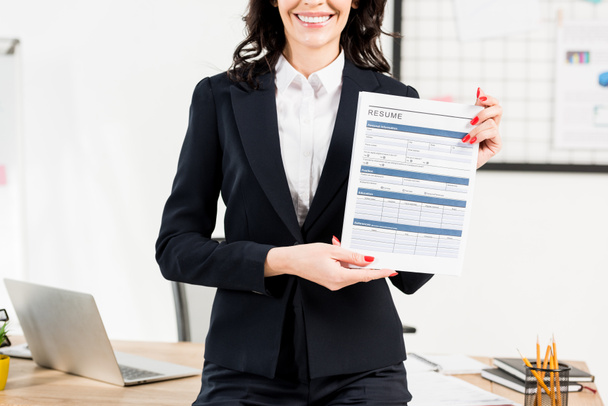 cropped view of cheerful woman holding resume in office  - Фото, зображення