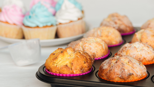 selectieve focus van smakelijke cupcakes met poedersuiker in cupcake tray - Foto, afbeelding