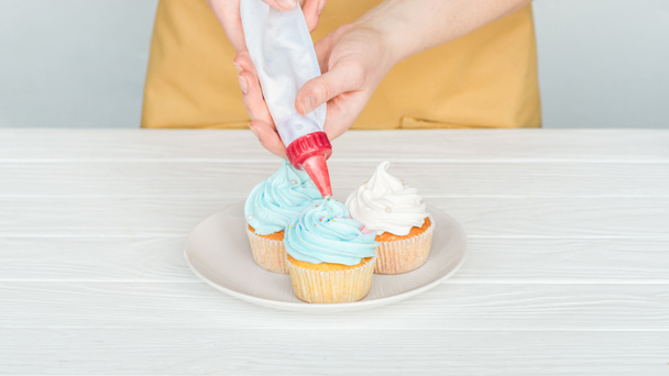 cropped view of woman decorating cupcakes with icing bag - Photo, Image