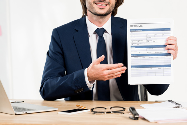 cropped view of cheerful recruiter gesturing while holding resume in office  - Foto, afbeelding