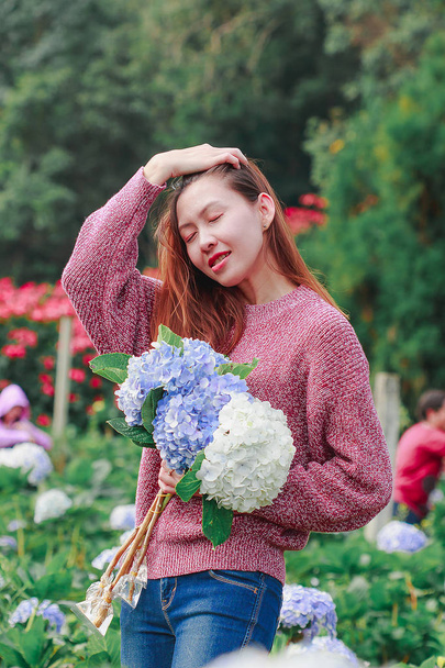 Женщины, стоящие с цветами гортензии в саду
 - Фото, изображение