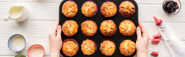 panoráma lövés nő gazdaság Muffin Pan asztalra sütőipari eszközök - Fotó, kép