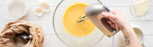 panoramic shot of woman mixing dough with hand mixer on wooden table - Photo, Image