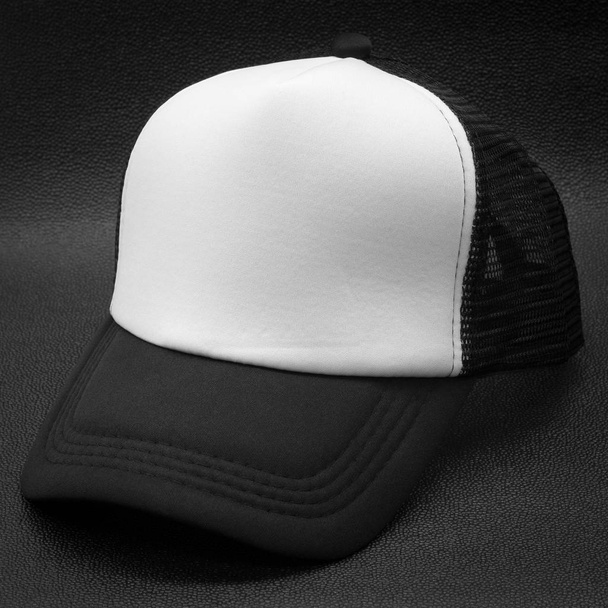Siyah kapak ve koyu arka planda beyaz yüzey. Tasarım için moda şapka. - Fotoğraf, Görsel