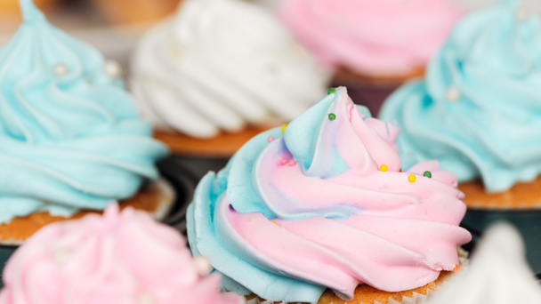 close up of delicious blue and pink cupcakes decorated with sprinkles in cupcake tray - Фото, зображення