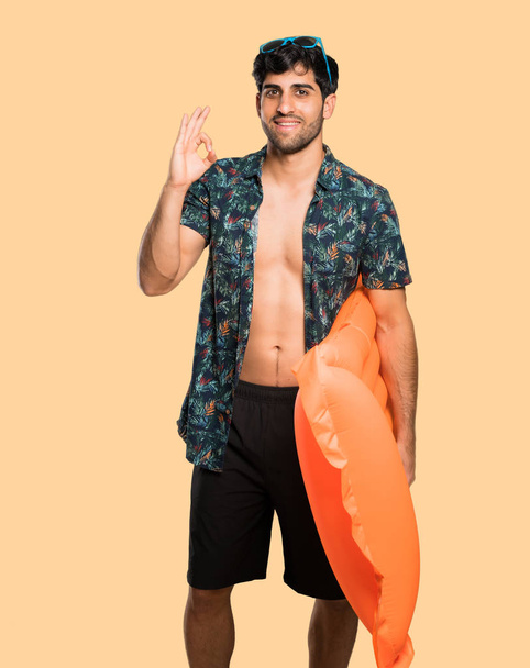 Man in trunks showing ok sign with fingers over isolated yellow background - Foto, Imagem