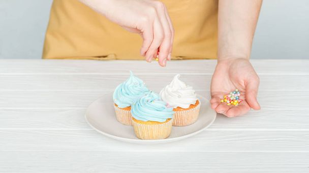 cropped view of woman decorating cupcakes with sprinkles - Fotoğraf, Görsel