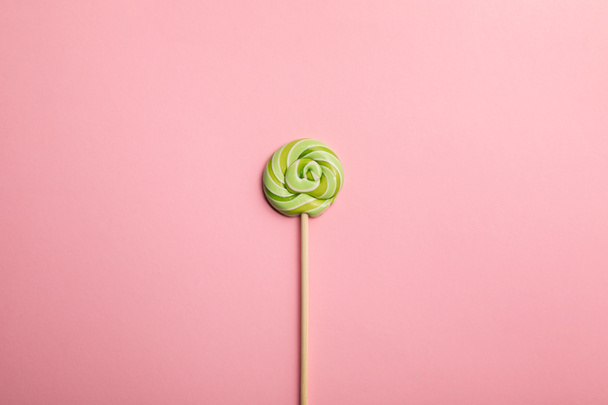 top view of delicious green swirl lollipop on wooden stick on pink background - Photo, Image