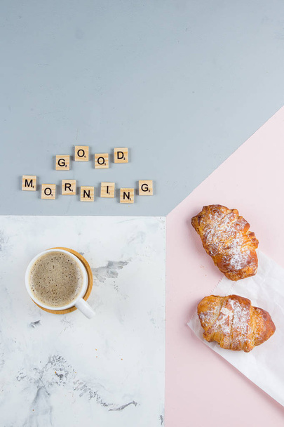 Hyvää huomenta aamiainen minimaalinen käsite. Kuppi kahvia, croissant ja tekstiä Hyvää huomenta tricolor tausta. Litteä
 - Valokuva, kuva