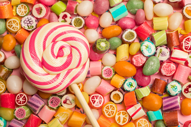 vista superior de brillantes deliciosos caramelos multicolores y piruleta
 - Foto, imagen