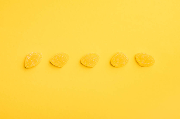 vista superior de deliciosas jaleas azucaradas en fila sobre fondo amarillo
 - Foto, Imagen