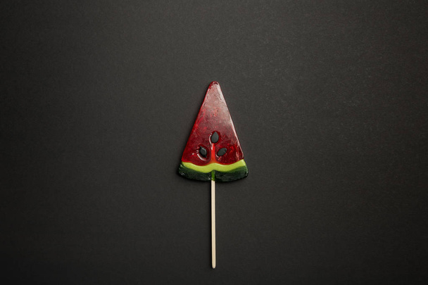 top view of watermelon tasty lollipop on wooden stick on black background - Photo, Image