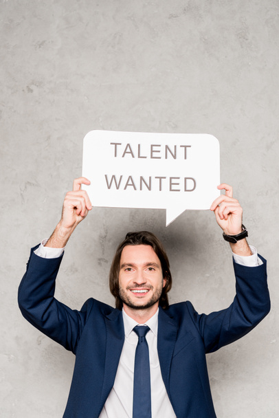 cheerful recruiter holding speech bubble with talent wanted lettering on grey - Photo, Image